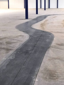 Clean trail of a scrubbing machine on industrial floor with adherent dirt