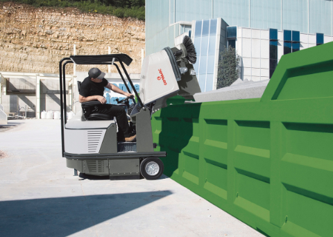 Man using a Comac CS120 floor sweeper equipped with automatic lifting system for unloading