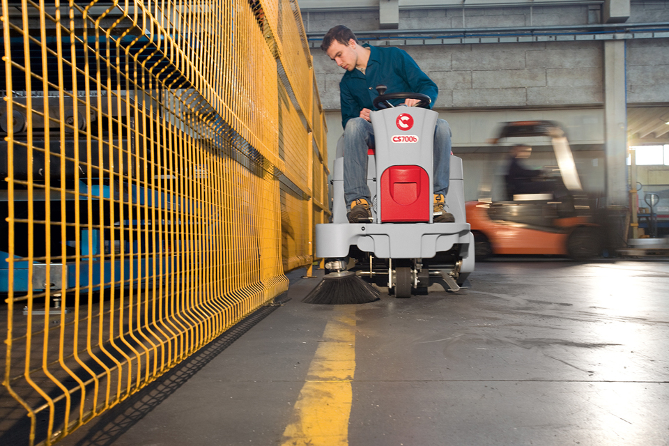 Boy sweeping the floors of a warehouse with a Comac CS800 sweeper