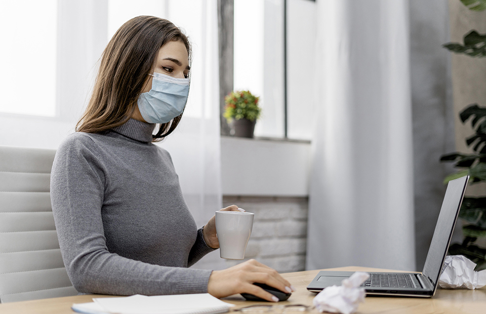 Girl wearing a medical mask while working in the office